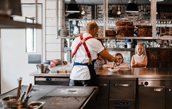Manlig kock och barn som lagar mat på sin restaurang