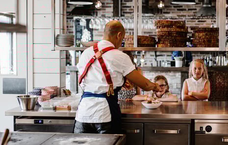 Manlig kock och barn som lagar mat på sin restaurang