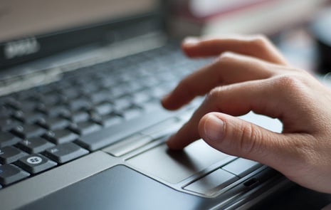 En hand som fingrar på laptops tangentbord.