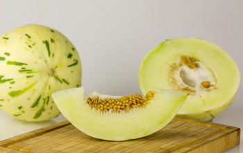 En uppskuren melon med en hel melon i bakgrunden.