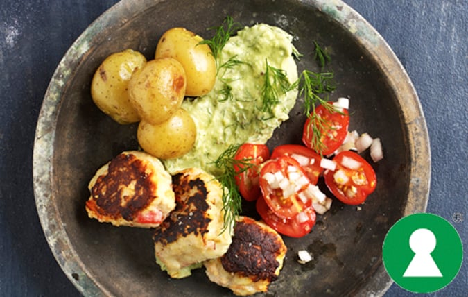 Tallrik med fiskedeller, avokadoröra, tomatsallad och kokt potatis.